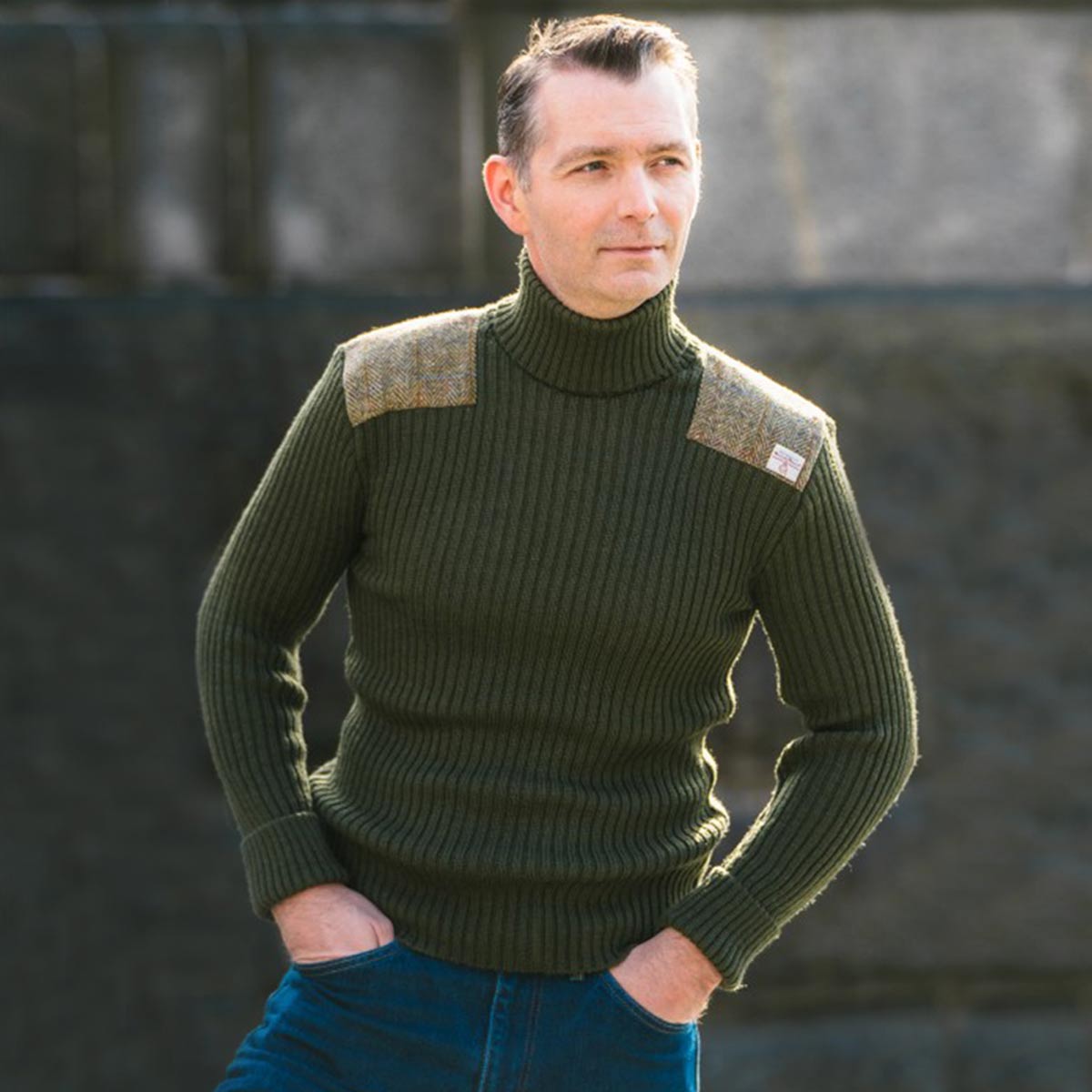 model wearing view of ghillie roll neck woolly pully sweater with harris tweed patches olive